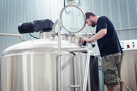 Brewer from Boneface checks brewing equipment